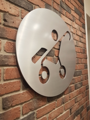 Custom solid brushed aluminium circular logo raised from the wall